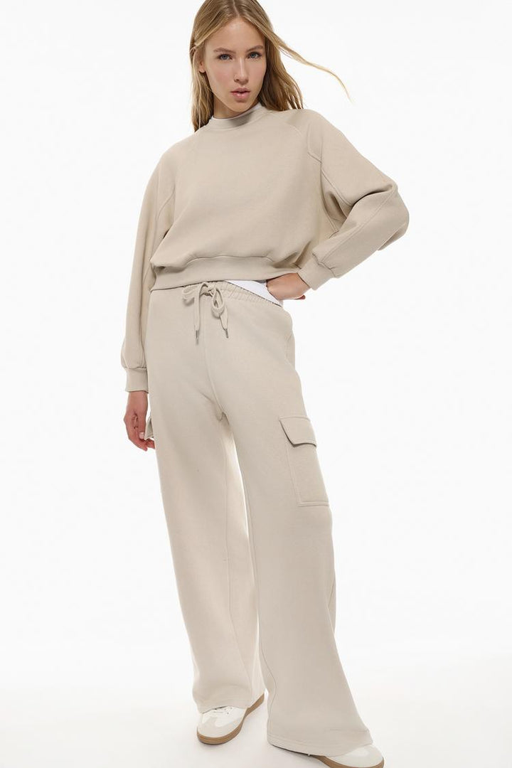 Full-body view of a women's beige basic cropped sweatshirt, showcasing its cropped length, relaxed fit, and minimalist design.