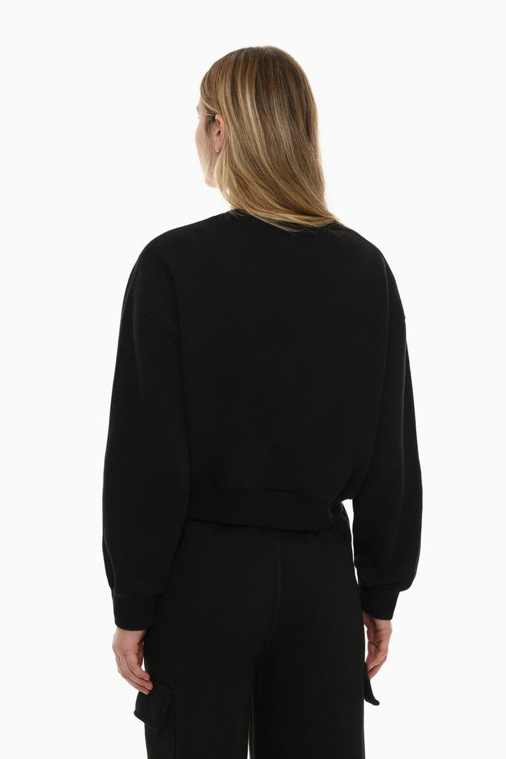 Zoomed-out view of a women's black basic cropped sweatshirt, highlighting the full design with its cropped length, relaxed fit, and minimalistic, modern look.