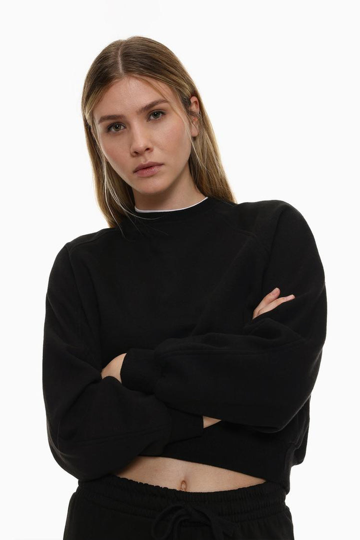 Zoomed-in view of a women's black basic cropped sweatshirt, highlighting the fabric texture, stitching, and cropped design details.