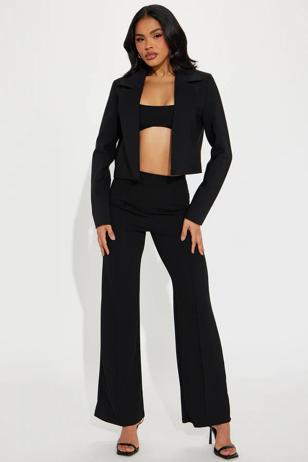 Model wearing a classic cropped black blazer with sharp lapels and a tailored fit, styled over a black bandeau top.