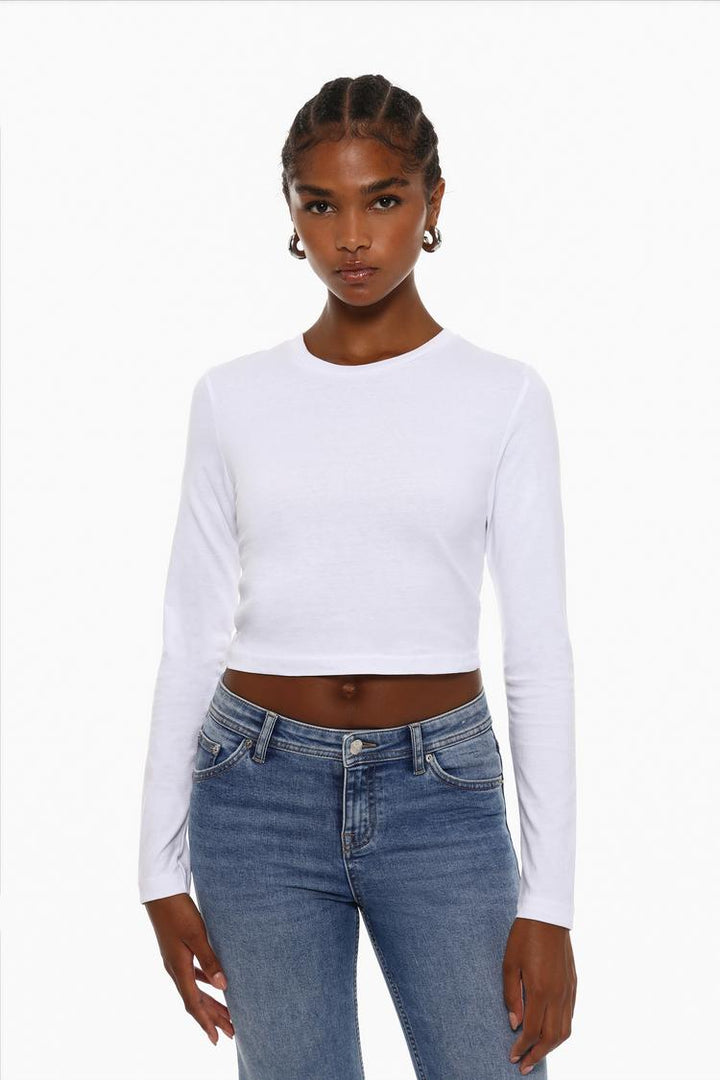 A white cropped long-sleeve top, designed for a sleek and stylish look. With its cropped fit and long sleeves, this versatile piece is perfect for layering or wearing on its own for a chic, casual outfit.