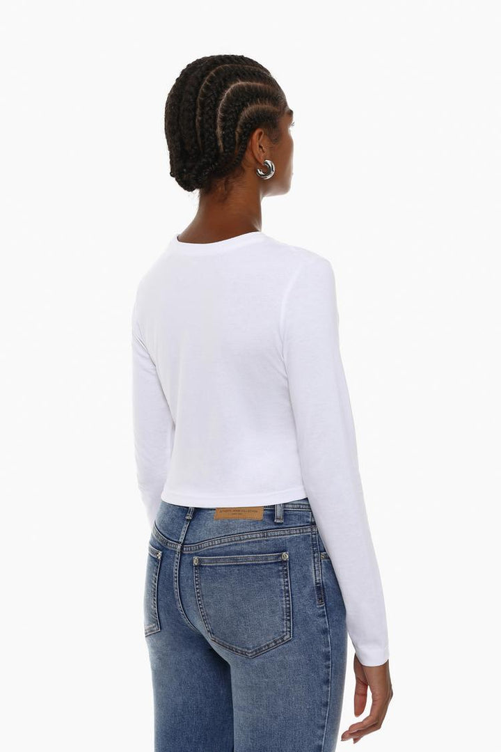 Side view of the white cropped long-sleeve top, showcasing its streamlined fit and cropped length, perfect for a chic and modern silhouette.