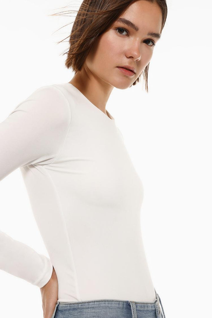 Side view of the white polyamide round neck bodysuit, showcasing the smooth, stretchy fabric and flattering fit that contours to the body for a sleek silhouette.