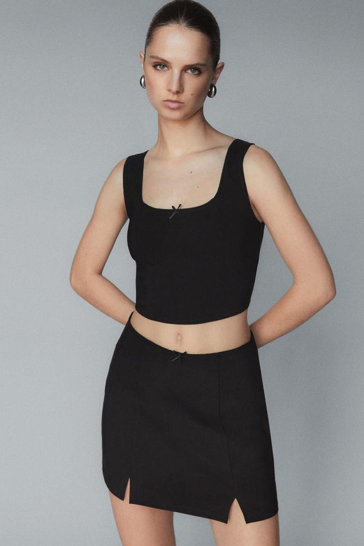 A black rustic strappy top with a bow, designed for a chic and feminine look. Featuring delicate straps and a playful bow detail, this top combines style with comfort for a versatile addition to any wardrobe.