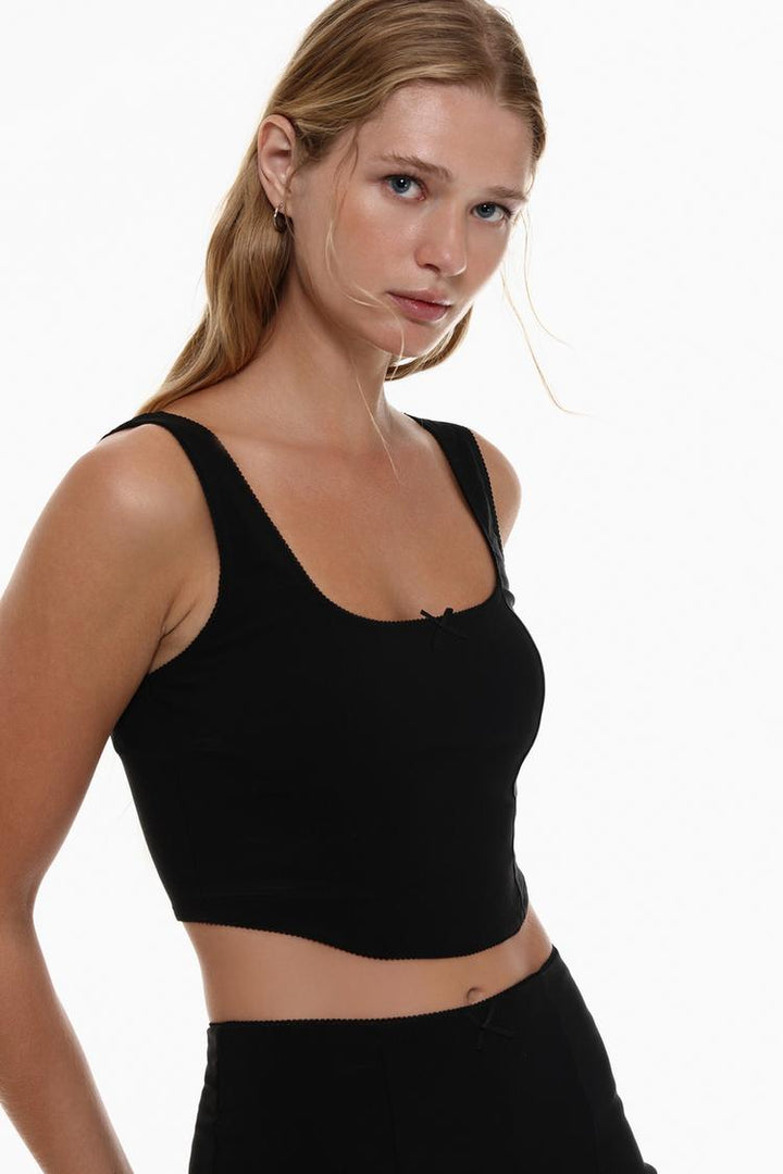 Body view of the black rustic strappy top with a bow, showcasing its delicate straps and playful bow detail for a chic, feminine look that flatters the figure.