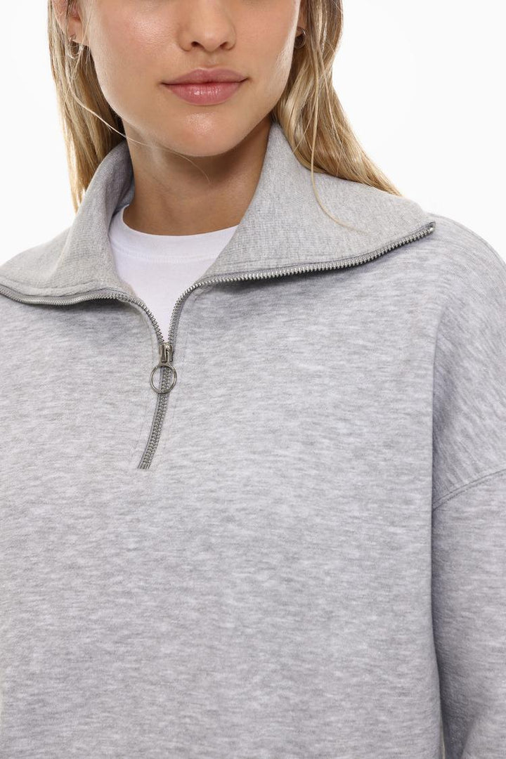 Body view of a women's grey sweatshirt with a zip-up collar, showcasing the relaxed fit and versatile design.