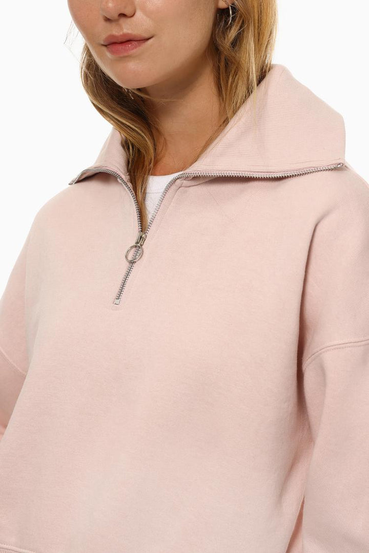 Side view of a women's pink sweatshirt with a zip-up collar, showcasing the relaxed fit and versatile design.