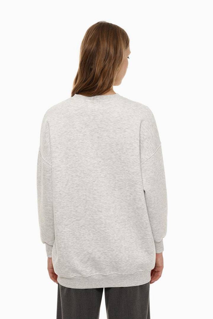 Zoomed-in back view of a women's grey oversized sweatshirt, highlighting the asymmetric design and fabric details.