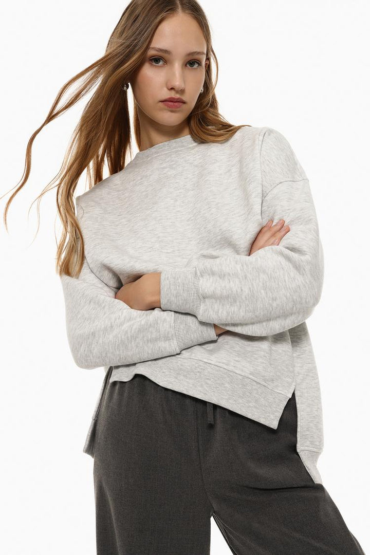 Showcasing the body of a women's grey oversized sweatshirt with an asymmetric design, highlighting the relaxed fit and modern styling.