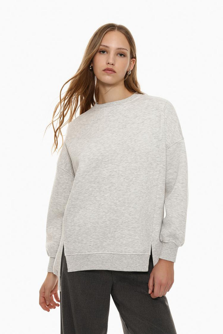 Zoomed-in view of the body of a women's grey oversized sweatshirt, highlighting the asymmetric design and fabric texture.