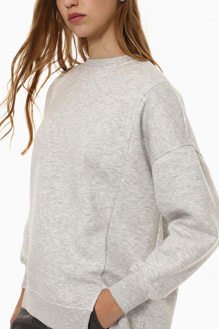 Side view of a women's grey oversized sweatshirt featuring an asymmetric design and relaxed fit.