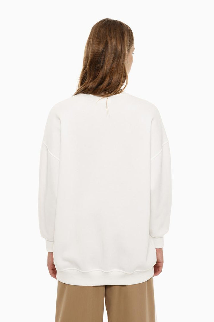 Back view of a women's white oversized sweatshirt featuring an asymmetric design and relaxed fit.