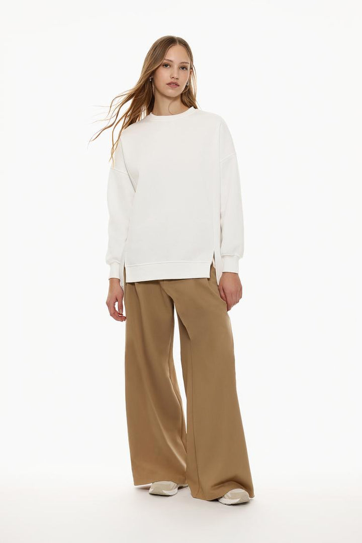 Full-body view of a women's white oversized sweatshirt with an asymmetric design, styled for a relaxed and contemporary look.