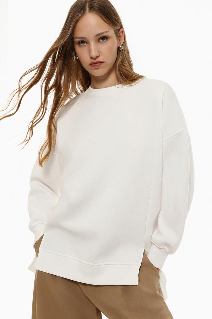 Zoomed-in view of a women's white oversized sweatshirt, highlighting the asymmetric design and fabric texture.