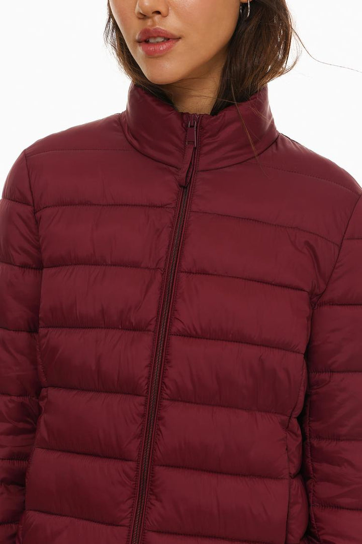 Close-up view of a basic lightweight puffer jacket in vibrant red, showcasing detailed stitching and smooth fabric texture.