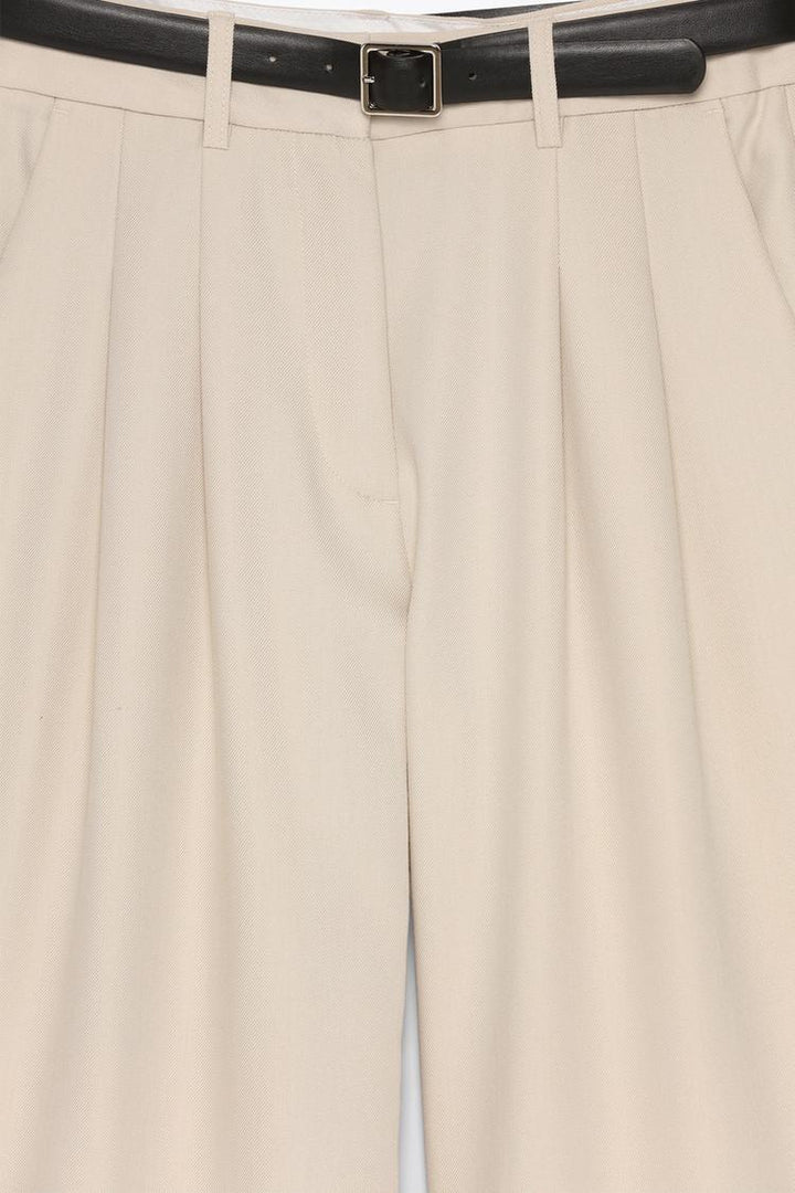 Product close-up of beige belted wide-leg trousers, focusing on premium fabric and craftsmanship