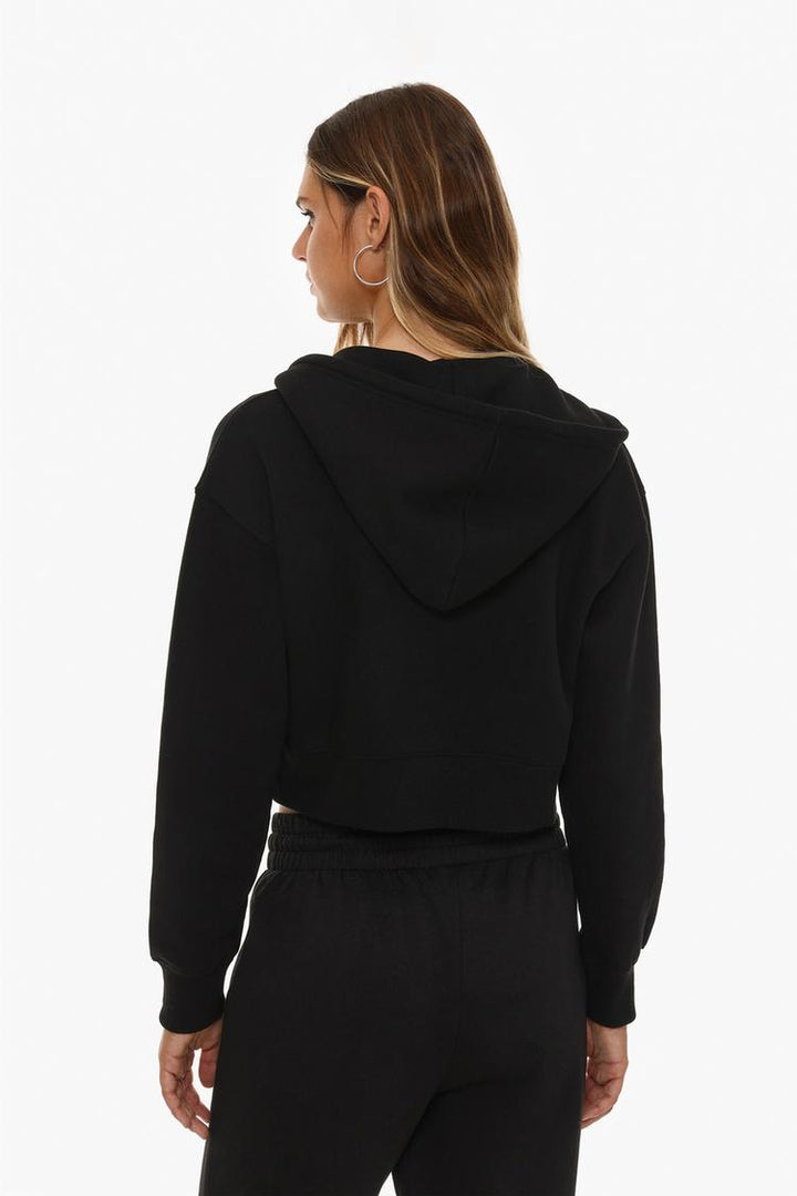 Back view of a women's black cropped jacket, showcasing its simple, modern design with a cropped length and relaxed fit.