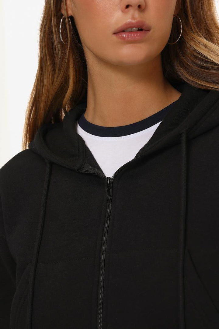 Zoomed-in view of a women's black cropped jacket, highlighting the fabric texture, stitching details, and modern design elements.