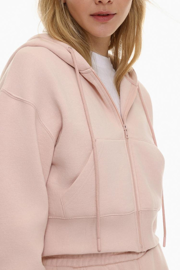 Zoomed-in view of a women's pink cropped jacket, highlighting the fabric texture, stitching, and design details.