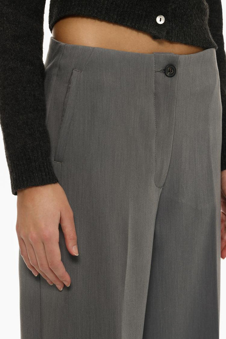 Side view of grey culottes without a waistband, highlighting their soft pleats and flowing fabric.