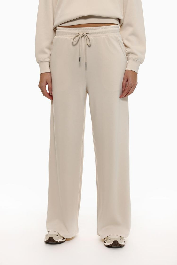 Side view of beige flowing sports trousers showcasing the smooth silhouette.