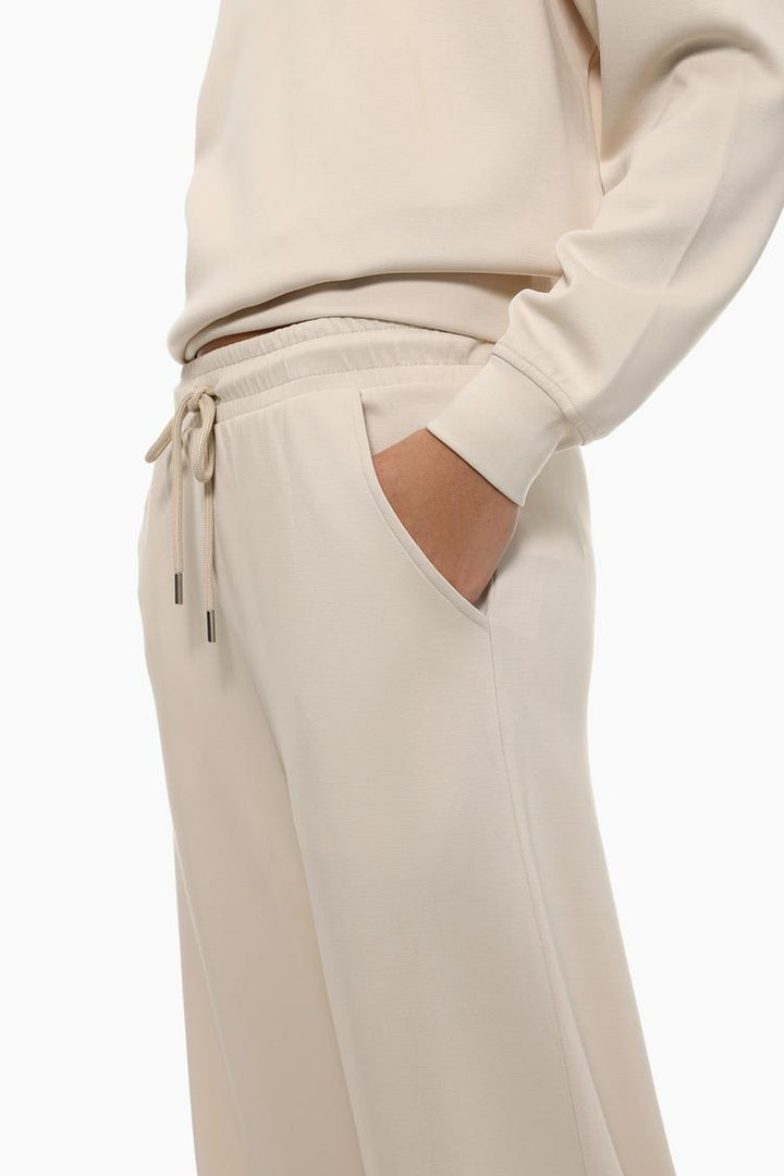 Full-body view of beige flowing sports trousers highlighting the overall fit.