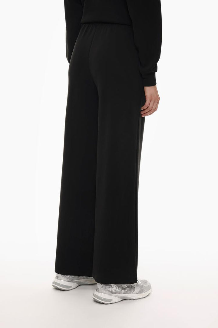 Back view of black flowing sports trousers highlighting the fit and style.