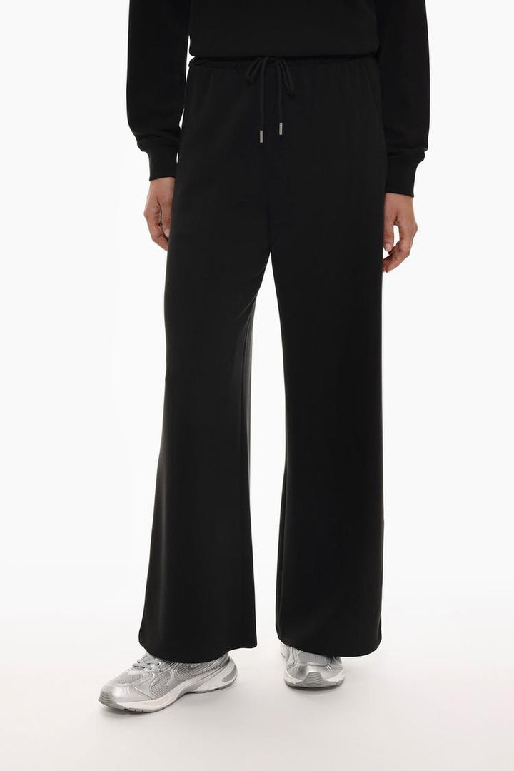 Front view of black flowing sports trousers emphasizing the sporty design.