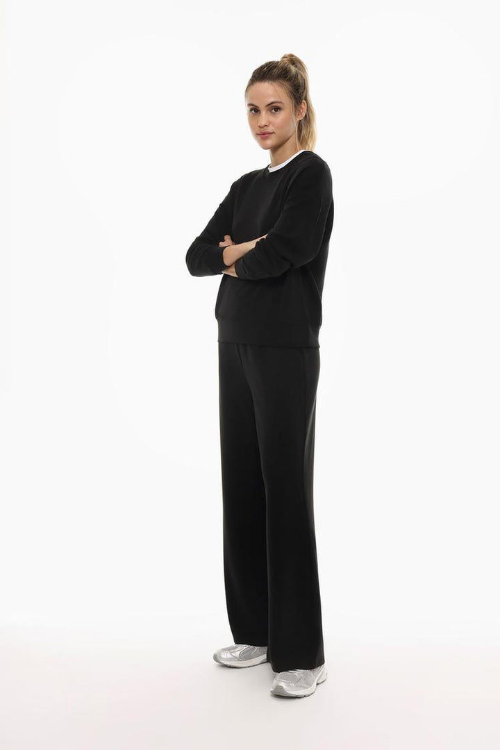 Full-body view of black flowing sports trousers showcasing the fit and length.