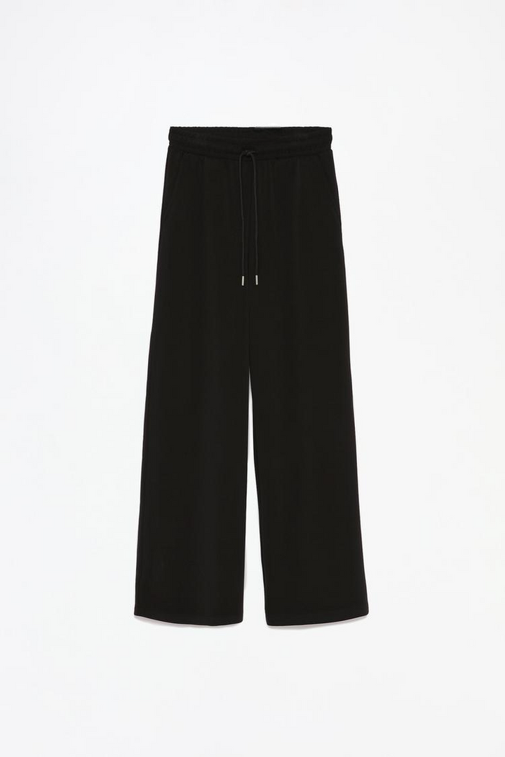 Product view of black flowing sports trousers showcasing the details.