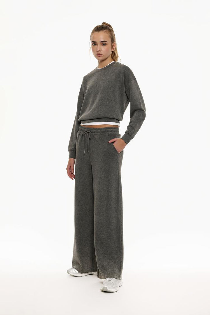 Full-body view of grey flowing sports trousers emphasizing the fit and length.