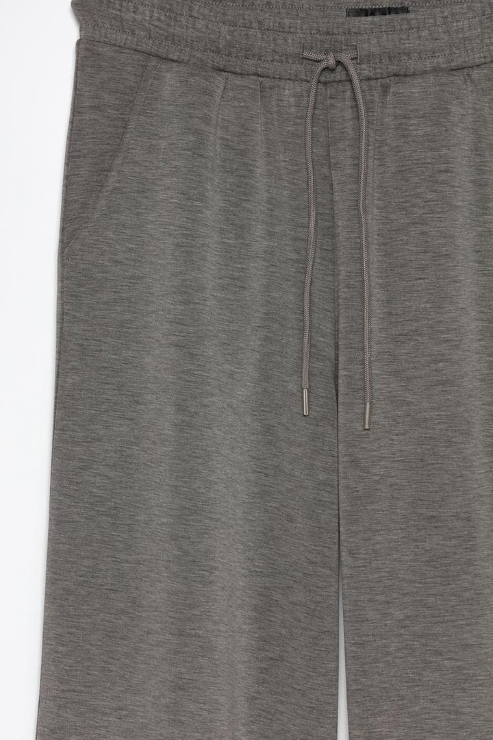 Product view of grey flowing sports trousers displaying the details and fabric.