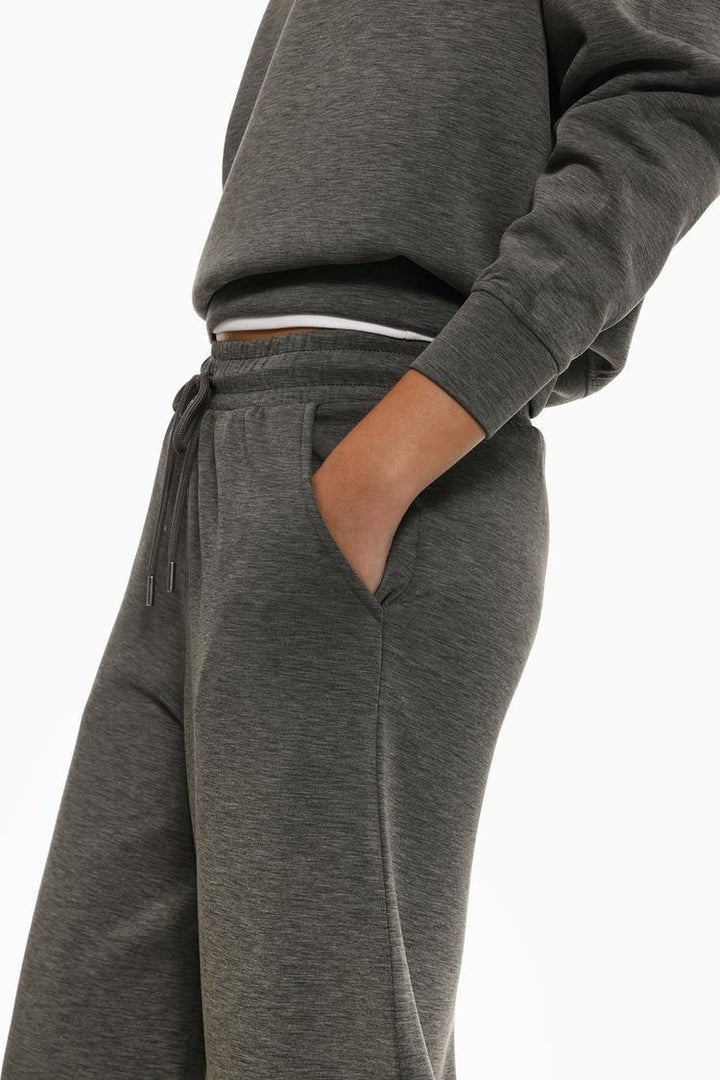 Side view of grey flowing sports trousers highlighting the sleek profile.