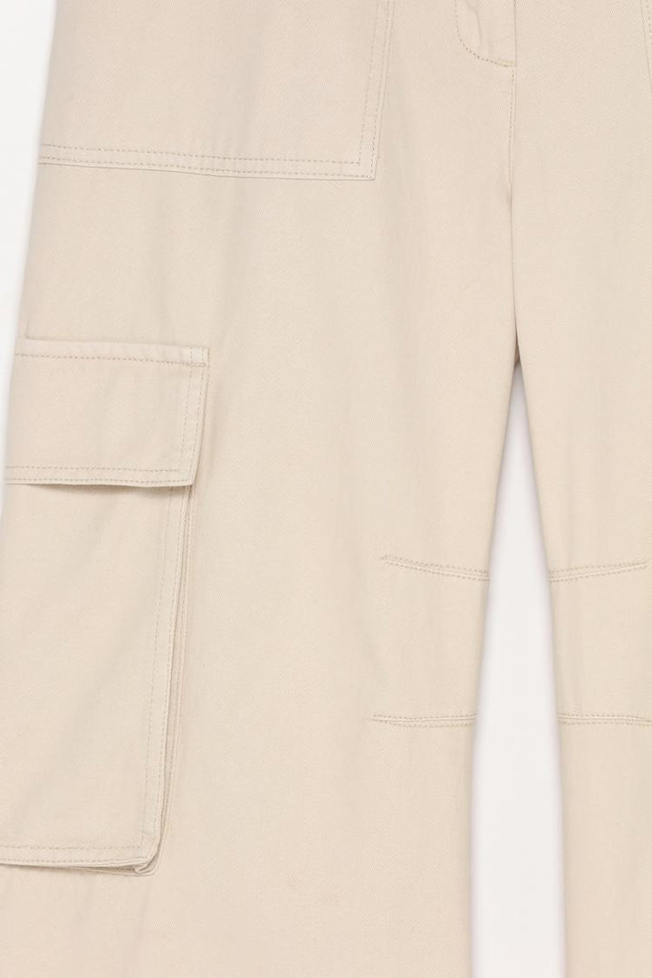 Close-up of the beige trousers, capturing the subtle dye variations and high-quality fabric.