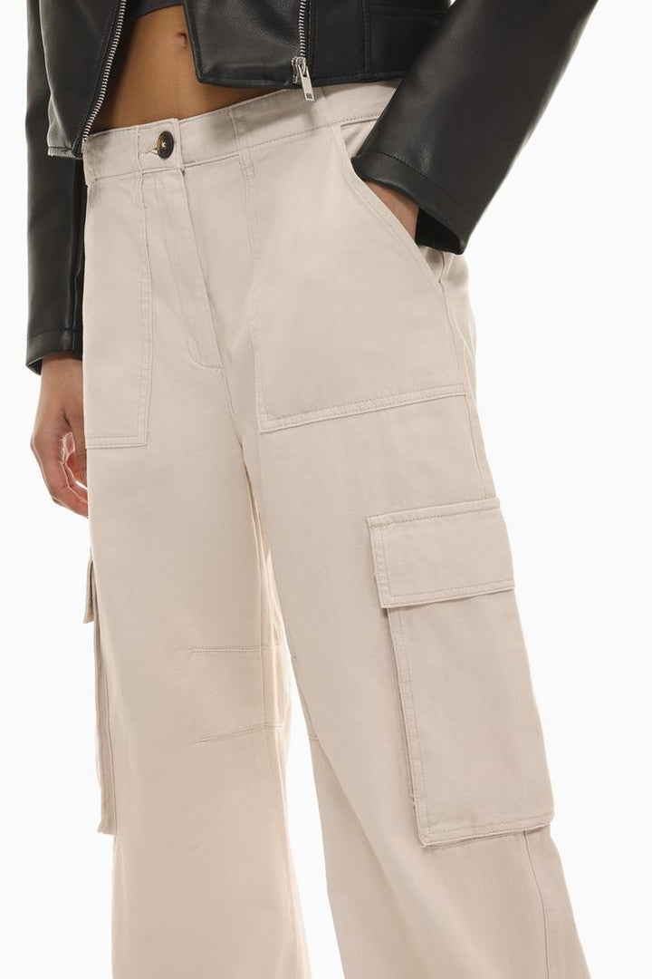 Side view of the beige trousers, showcasing the spacious side pockets and clean, minimalist seams.