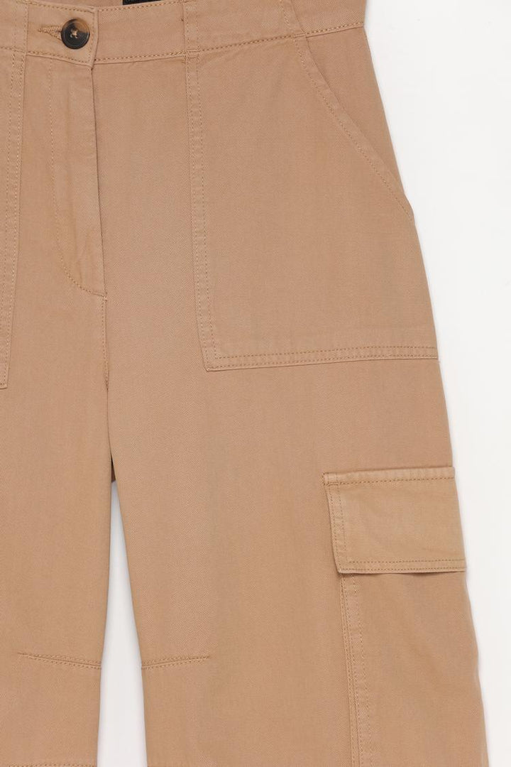 Detailed close-up of the brown trousers, highlighting the unique garment-dye finish and stitching.