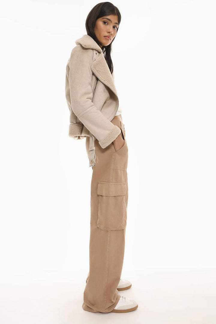 Side profile of the brown cargo trousers, emphasizing their tailored fit and deep side pockets.