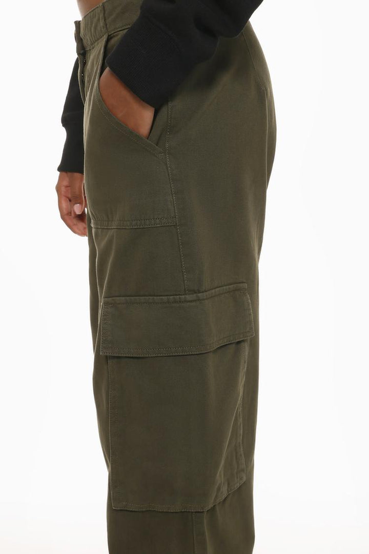 Side profile of the dark green trousers, featuring spacious cargo pockets and subtle seam detailing.