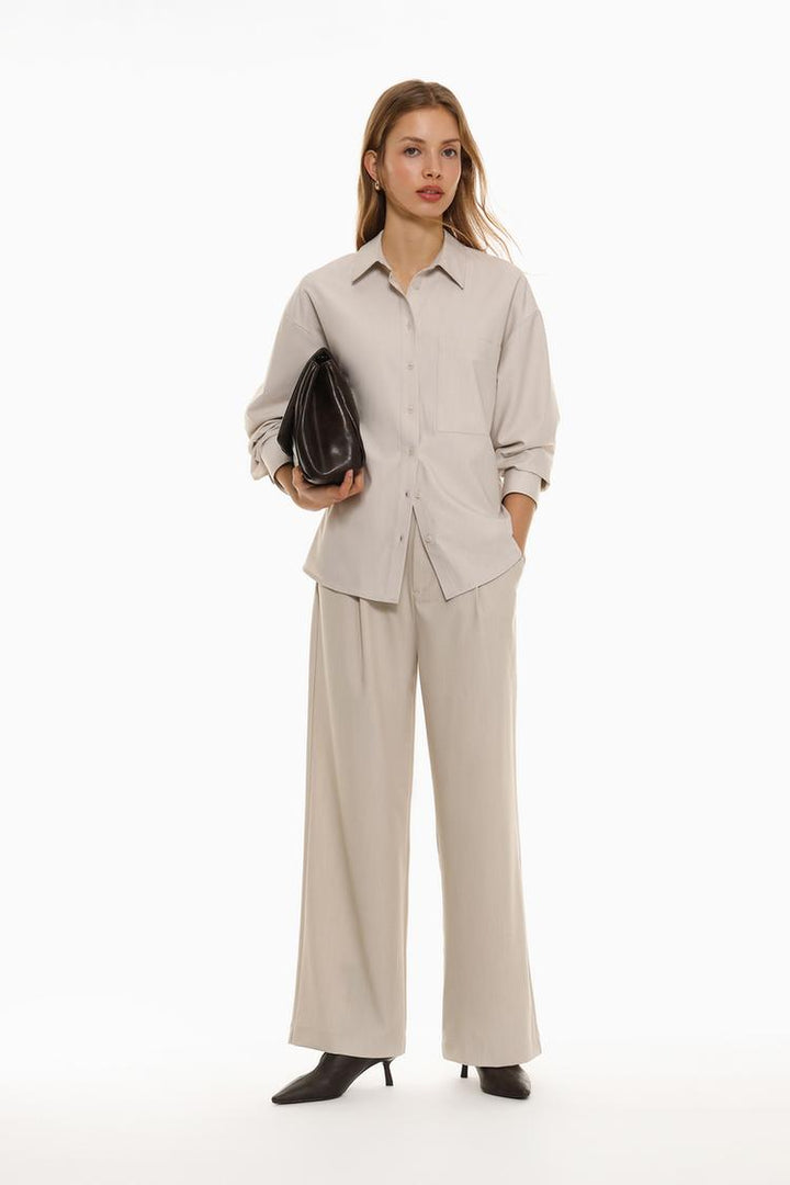 Full-body view of beige loose-fitting wide-leg trousers, highlighting their relaxed and flattering fit