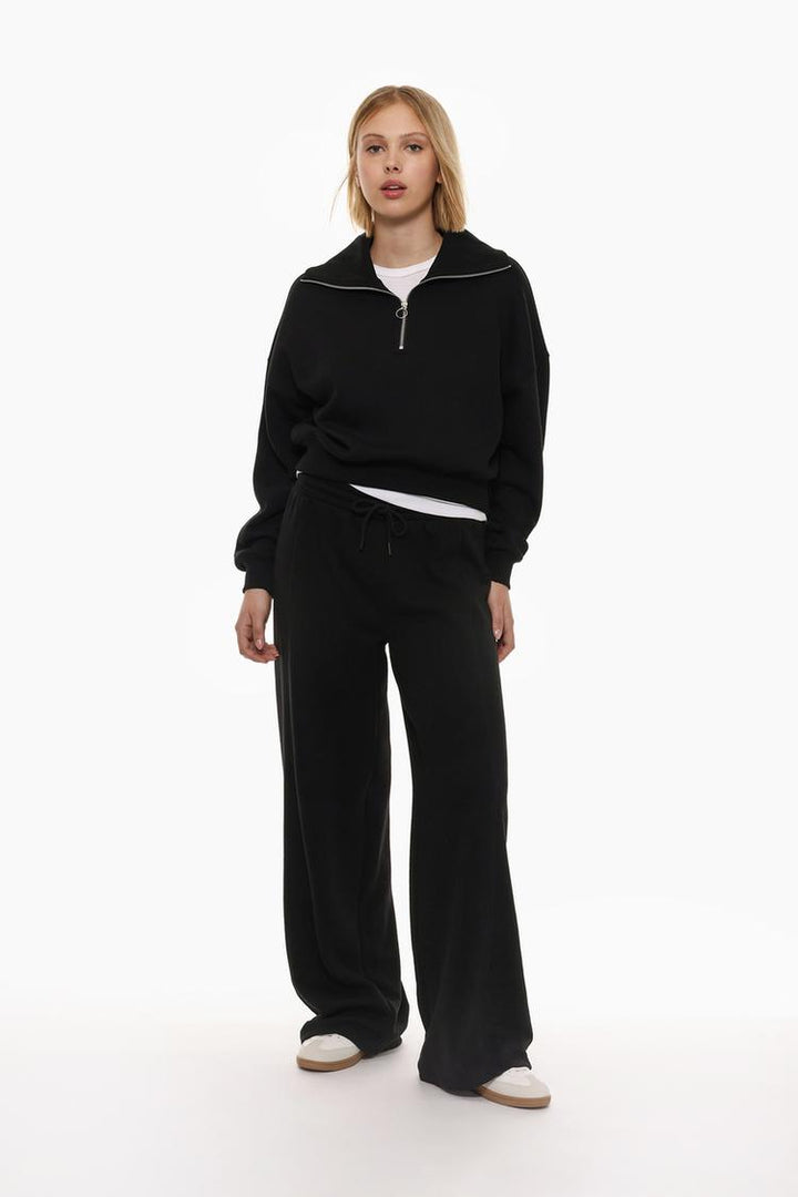 Image of the black oversize plush trousers, highlighting the relaxed and plush texture of the fabric.