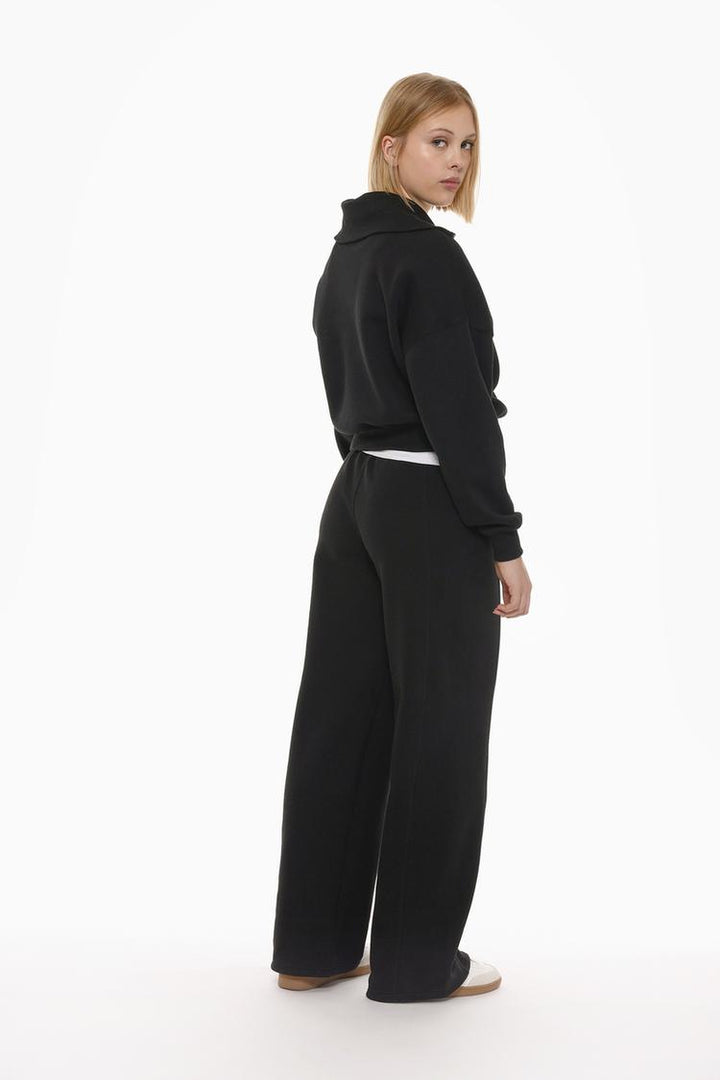 Back view of the black oversize plush trousers, giving a clear look at the fit and design from the rear.