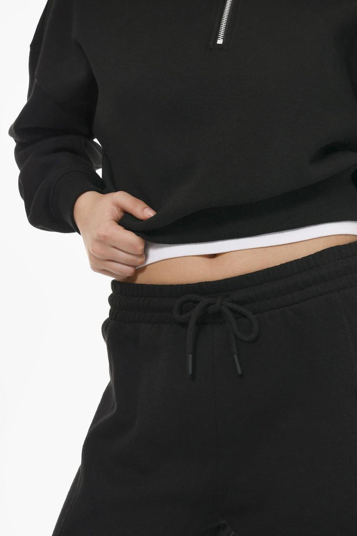 Image of someone wearing the black oversize plush trousers, focusing on the overall appearance and fit as part of an outfit.