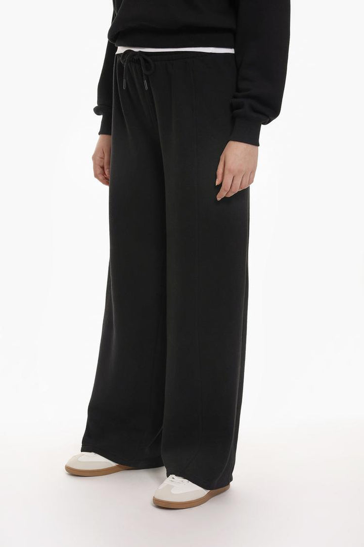 Front view of the black oversize plush trousers, showing the loose fit and the plush material that gives a cozy and comfortable look.