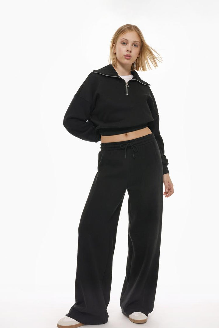 Full-body shot of someone wearing the black oversize plush trousers, demonstrating how they look when styled as part of an outfit.