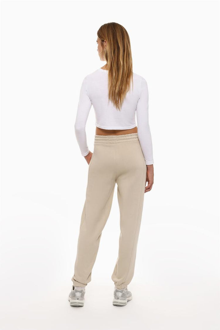 Back view of the beige oversized tracksuit trousers, emphasizing the fit around the waistband and relaxed style.