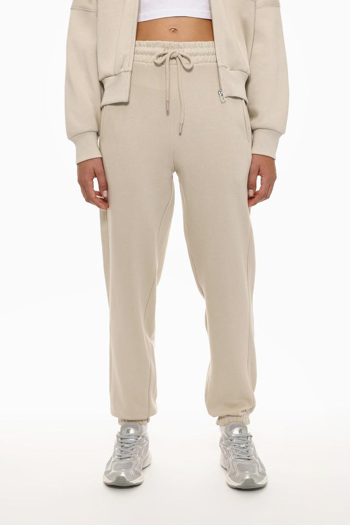 Front view of the beige oversized tracksuit trousers, showcasing the relaxed fit and simple design.