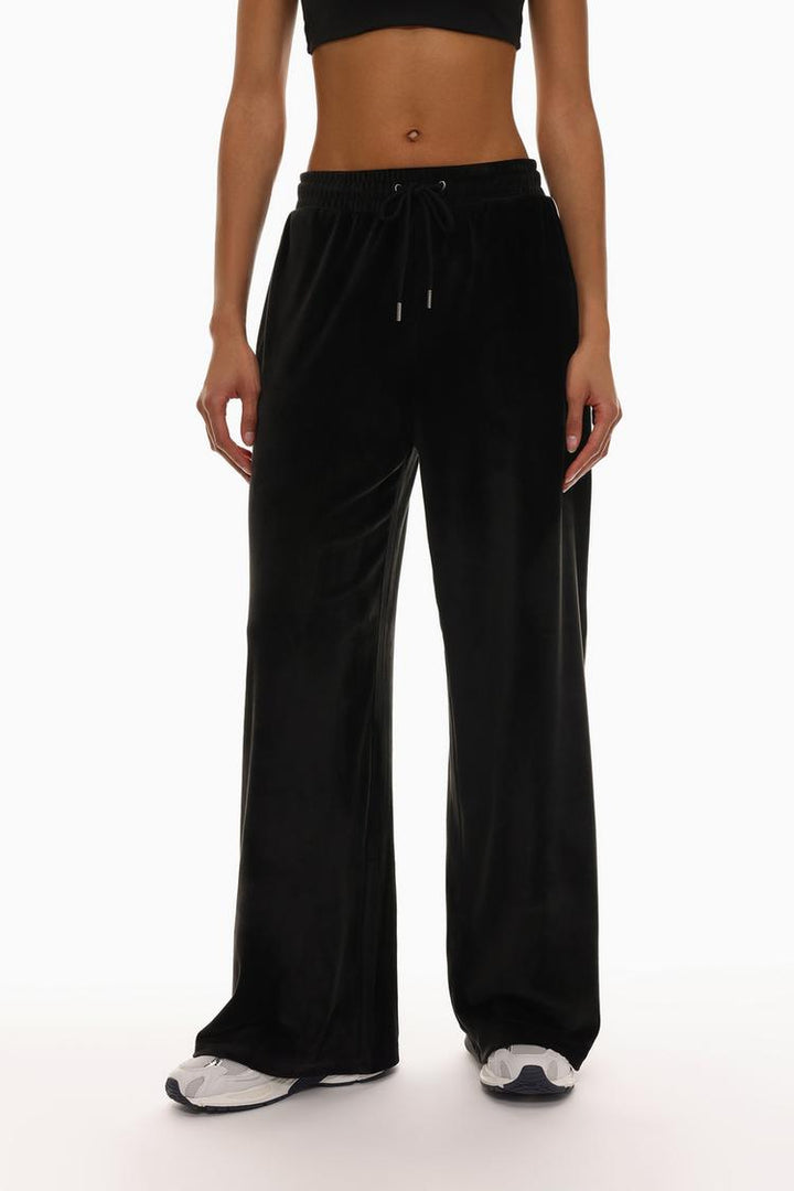 Front view of black oversized velvet trousers highlighting the waist and leg fit.
