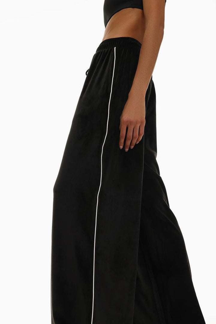 Side view of black oversized velvet trousers to show the overall silhouette.
