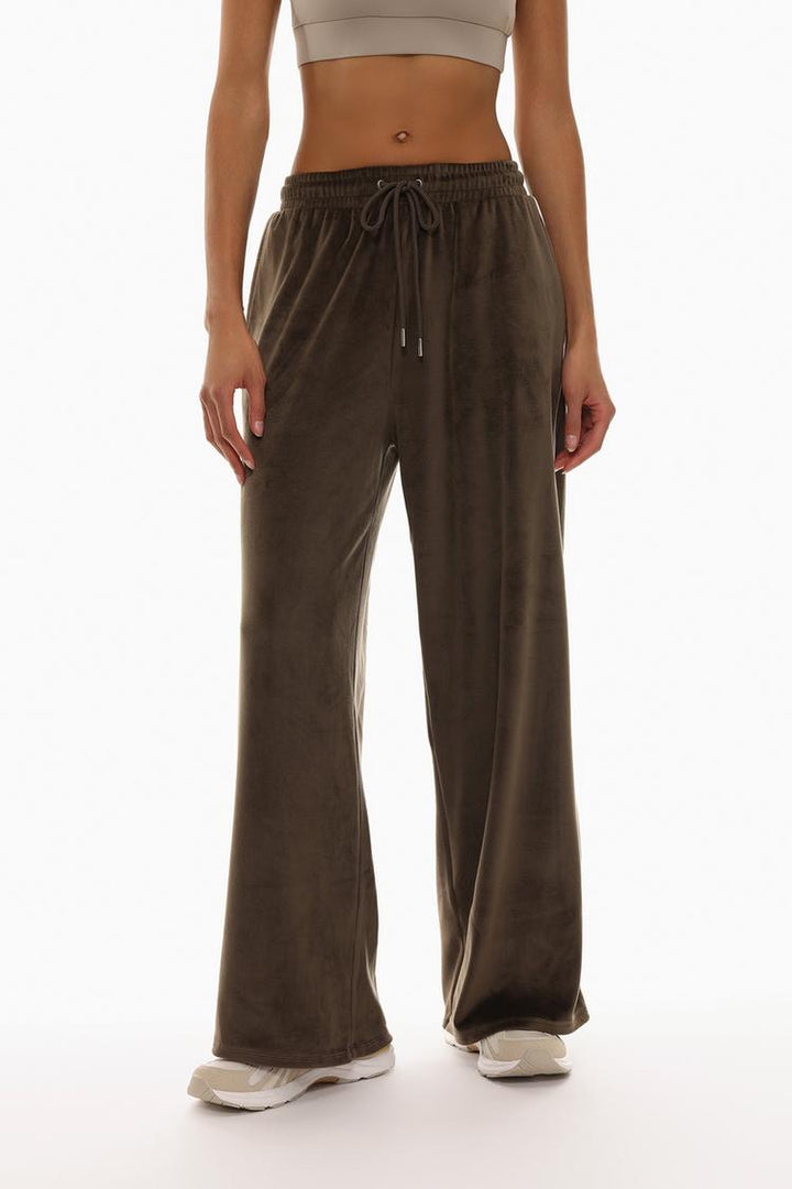 Body shot of brown oversized velvet trousers focusing on the overall fit.
