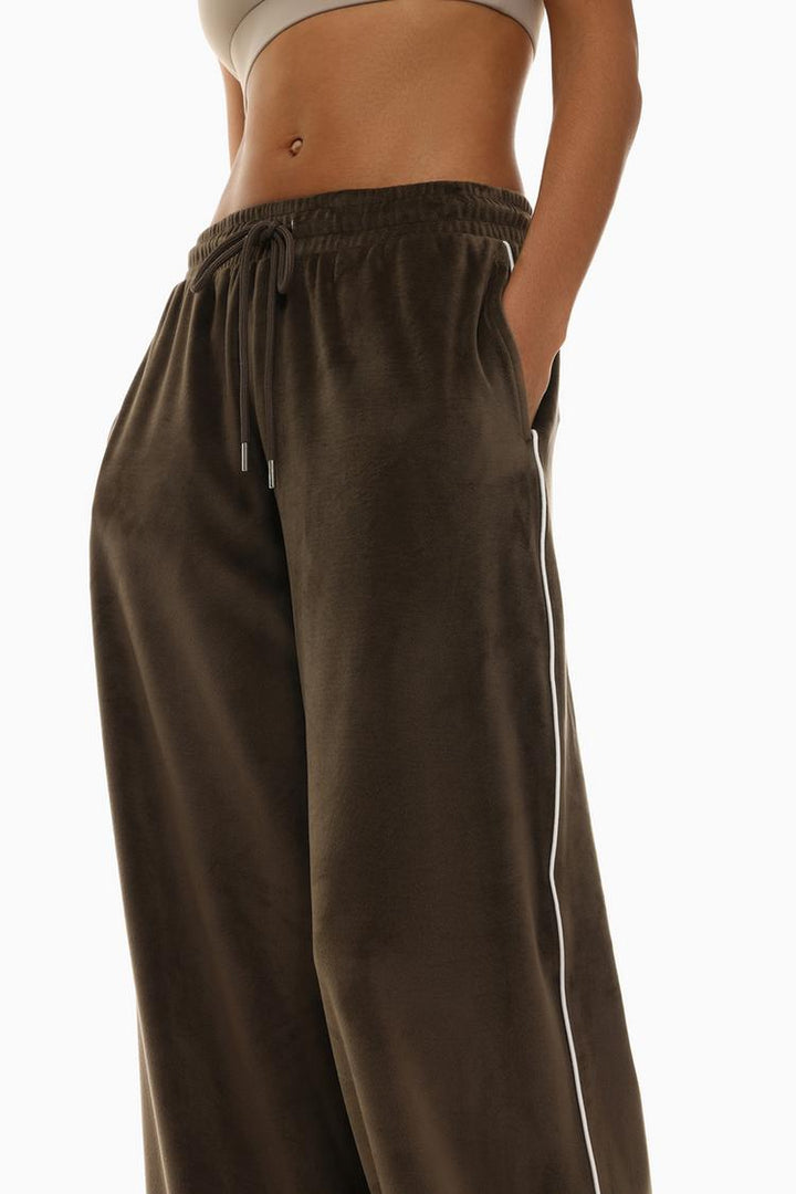 Side view of brown oversized velvet trousers showing the overall silhouette.
